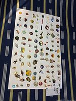 Full view of approximately 90 assorted enamel pins on white board