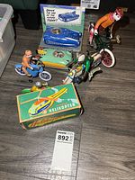 Group view of all tin toys on floor, showing vehicles, figures, and boxed items