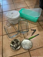 Group shot showing all items: salad spinner, Tupperware container, two glass loaf dishes, cookie cutter tin, corkscrew, pen