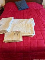 Folded ecru linens with ivy embroidery on bed