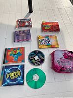 All media items laid out including jewel-case CDs, loose discs, pink karaoke case