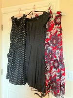 Three dresses hanging: black polka dot, black micro-dot, red floral