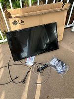 Television with box, power cord, Ethernet cable, remote and accessories visible