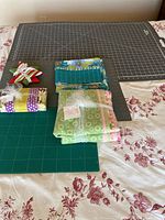 All items on bed: large grey mat, green mat, four quilting fabric bundles