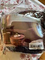 Front of packaged waffle-texture brown sofa slipcover displaying product image and seating size options