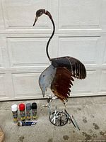 Full view metal heron sculpture with paint supplies