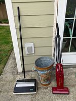 Overall view of carpet sweeper, vacuum, and umbrella stand