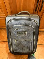Front view of blue Tommy Hilfiger suitcase showing logo patch and front pocket
