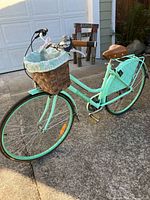 Full view of mint green step-through bicycle with basket and rear rack