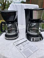 Both coffee makers side by side with carafes and manual
