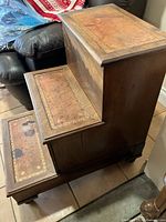 Side view showing three wooden steps with leather inlays and bun feet