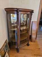 Full view of oak curved-glass china cabinet showing door, shelves, and paw feet