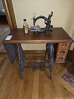 Sewing machine on closed wood cabinet, cast-iron treadle base visible