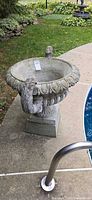 Full view of concrete urn on pedestal beside pool
