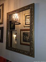 Full view of rectangular ornate gilt wall mirror hung on wall