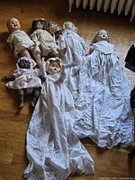 All seven baby dolls laid out showing garments and relative sizes