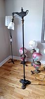 Full view of tall ornate metal bridge floor lamp with cast iron base on hardwood floor