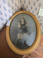 Front view of oval gold-tone frame with convex glass and portrait photo