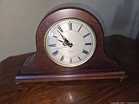Front view of wooden tambour mantel clock displaying dial and bezel