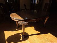 Full view of dining table in room showing oval top and carved legs