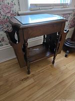 Full view of wooden side table showing glass top, magazine racks, lower shelf