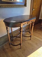 Full view of wood console table showing serpentine top, fluted apron and legs