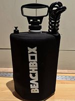 Front view showing BEACHBOX logo, reservoir shape, cap, hose attachment