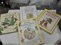 All four Beatrix Potter books laid out on cloth surface