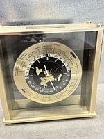 Front view of clock showing dial, world time cities, and case