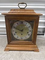 Front view of wooden Seth Thomas mantel clock showing dial and handle