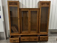 Full view of four-piece oak wall unit showing two tall narrow curios, wider center cabinet, and three lower drawers