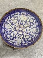Interior of brass bowl showing blue, white and gold floral enamel