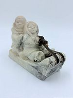 Front-left view of stone carving showing both figures and sled