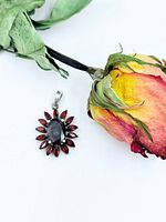 Front view of pendant next to dried rose showing overall design and scale