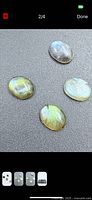 Four oval labradorite cabochons on dark background showing flash