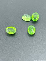 Four oval green cabochon stones on dark background