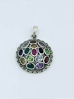 Front view of round sterling silver pendant with multicolour gemstones and marcasite frame