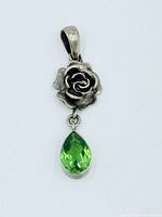 Front view of sterling silver rose pendant with dangling peridot