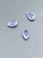 Close-up of three loose tanzanites on textured background