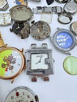 Overview of watch parts focusing on Gucci case and Swatch watch