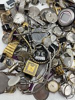 Pile of assorted watches and parts on white surface