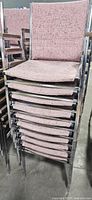 Stack of pink fabric upholstered metal armchairs