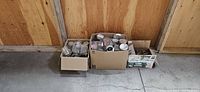 Three boxes filled with assorted glass canning jars and lids