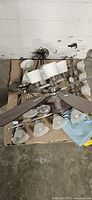 Ceiling fan, two chandeliers, and loose frosted glass shades arranged on pallet