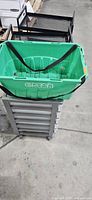 Grey 7-drawer cart with green tote on top and part of black carts visible