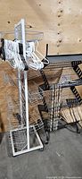 White wire basket rack with plastic hangers alongside black metal 3-tier display rack with wooden hangers and metal hooks