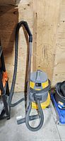 Overall view of yellow and grey wet dry shop vacuum with hose and chrome wand