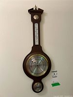 Full view of wooden banjo weather station on wall