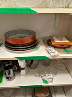 Shelf view with stacked plates and bowl beside assorted trivets