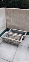 Two rectangular concrete planters side by side, showing overall form and decoration